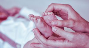Petits pieds de bébé tenus délicatement dans les mains de sa mère