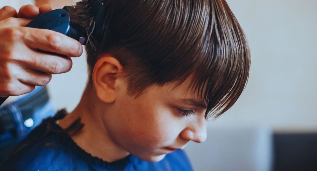Garçon se faisant couper les cheveux à la tondeuse sur les côtés